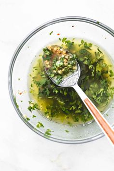 a glass bowl filled with broccoli and chickpea soup next to a wooden spoon