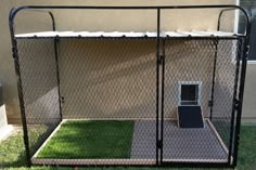 a dog kennel in the grass with its door open