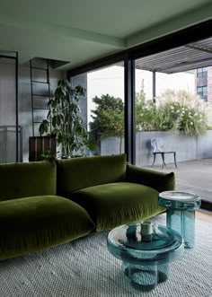 a living room filled with furniture next to a large glass window covered in potted plants