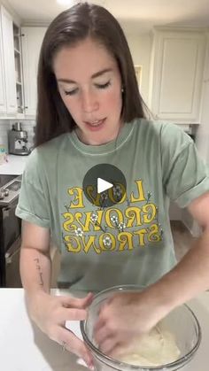 a woman in a green shirt is making some food on a counter top with a mixing bowl