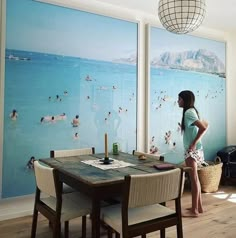 a woman standing in front of a painting on the wall next to a dining room table