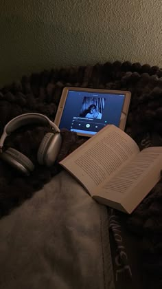 an open book and headphones on a blanket