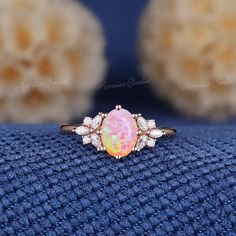 an opal and diamond ring sits on a blue cloth