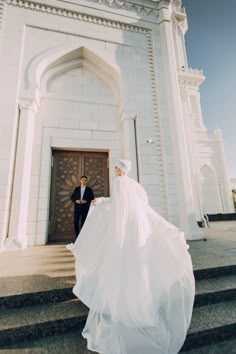 a man and woman standing in front of a white building