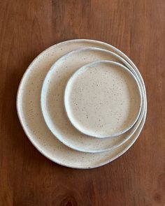 three white plates sitting on top of a wooden table