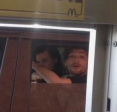 two people sitting in a car looking out the window at mcdonald's sign above them