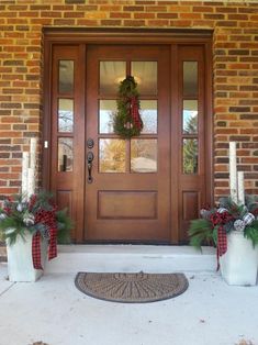 the front door is decorated for christmas with wreaths and candles