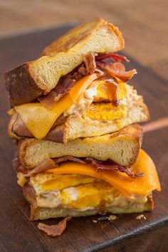 three sandwiches stacked on top of each other with bacon, cheese and egg in between them