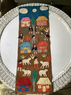 a table runner with an image of people and animals on it, sitting on top of a white plate