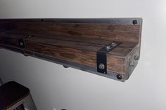 a shelf made out of wood with metal brackets on the top and bottom, hanging from a wall