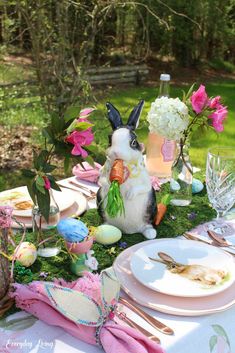 a table set with plates, flowers and bunny figurines for easter dinner in the woods