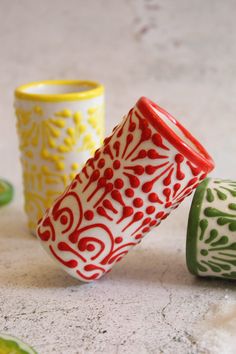 three different colored cups sitting on top of a table