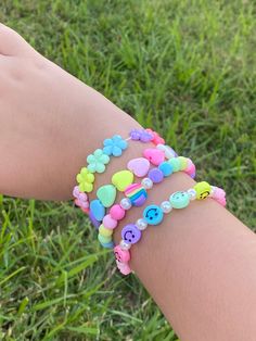 a child's hand holding onto a bracelet with buttons and letters on it in the grass