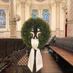 a wreath on top of a wooden bench in a church with stained glass windows behind it