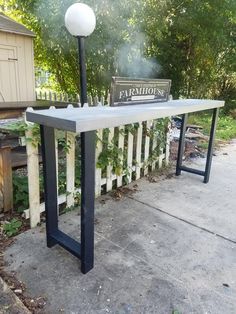 a table with a sign on it sitting in front of a fence