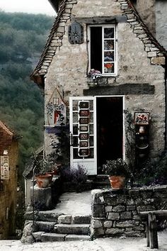 an old stone house with potted plants on the front and steps leading up to it