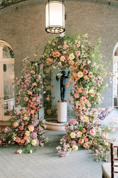 an archway with flowers and a statue in it