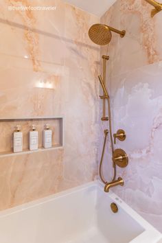 a bathroom with marbled walls and gold fixtures, including a bathtub faucet