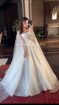 a woman in a white wedding dress taking a selfie with her cell phone while standing on a red carpet