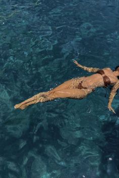 a woman floating in the ocean on top of a surfboard