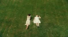 two people laying in the grass with their arms around each other