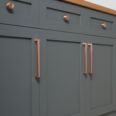 a gray kitchen cabinet with glass knobs on the doors and drawer pulls in place