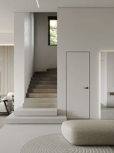 an open door in the middle of a white room with stairs and tables on either side