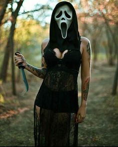 a woman in a black dress with a mask on her face and holding a knife