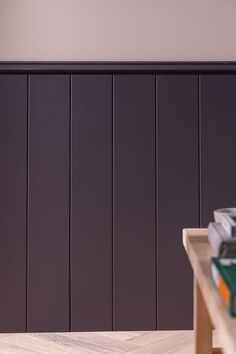 there is a table with books on it in front of a wall that has vertical paneling