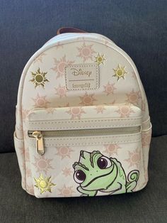 a small white backpack with a frog on it's front and side zippers