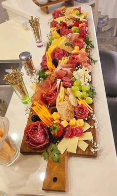 a long wooden platter filled with different types of cheeses and meats on top of a table