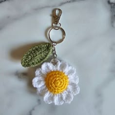 a crocheted flower keychain with a green leaf hanging from it's center