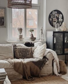 a living room filled with furniture and a cat laying on top of a couch next to a window