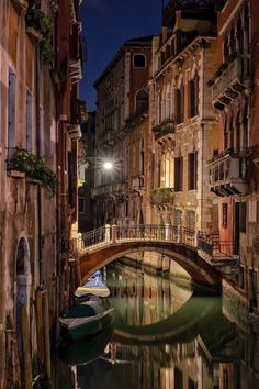 a bridge over a river with boats on it and buildings in the background at night