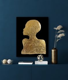 a gold sculpture sitting on top of a blue shelf next to a vase filled with flowers