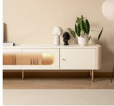 a white sideboard with two plants on it