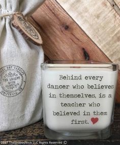 a small glass candle with a quote on it next to a bag and some other items