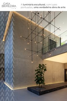 a plant is sitting in the middle of a room with stairs and lights hanging from the ceiling