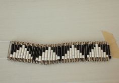 a black and white bracelet with squares on it sitting on top of a wooden table