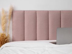 an open laptop computer sitting on top of a bed next to a tall grass plant