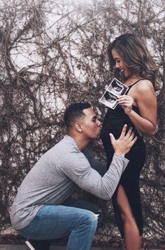 a man kneeling down to kiss a woman's face in front of a wall