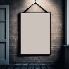 an empty frame hanging on a brick wall next to a door with a light above it