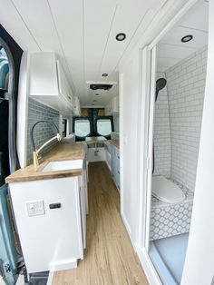 the interior of an rv with wood flooring and white walls, along with wooden counter tops