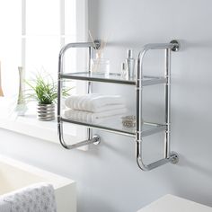 a bathroom shelf with towels on it next to a bath tub and window in the background