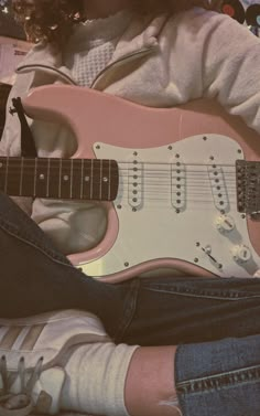 a person sitting on the floor with a pink guitar in front of their face and feet