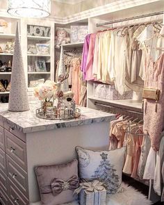 an organized closet with clothes hanging on the racks and other items sitting on top of it