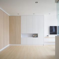 an empty room with wooden floors and white walls, has a television on the wall