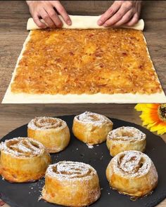 doughnuts and pastries on a black plate next to a wooden table with sunflower