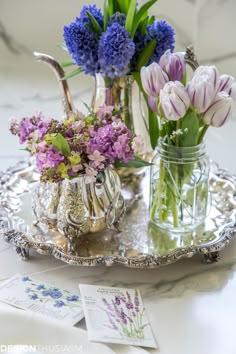 flowers are in vases on a silver tray