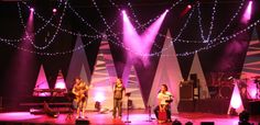 a group of people standing on top of a stage next to microphones and lights